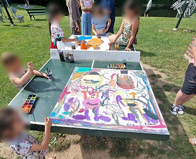 Große Leinwände (1x1m) auf der Tischtennisplatte werden von Kindern mit Gouache bemalt.