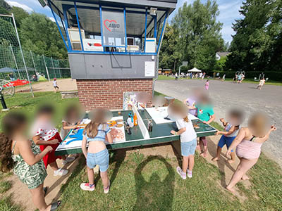 Kinder malen auf Leinwänden an einer Tischtennisplatte am Aggerstrand